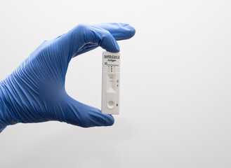 detalle de una mano con guantes azules tomando una prueba de antígeno negativa, prueba de...
