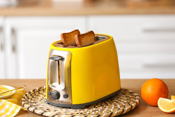 Yellow toaster with bread and orange slices on table in kitchen