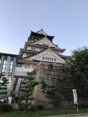 A famous historical sightseeing spot in Japan Osaka Jo castle with a modern elevator above the stone wall in the park in summer under the blue sky taken from the low angle
