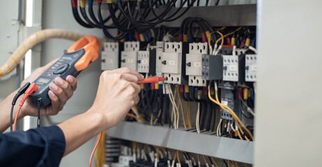 Electrician engineer work tester measuring voltage and current of power electric line in electical cabinet control , concept check the operation of the electrical system .