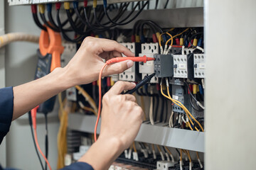 Electrician engineer work tester measuring voltage and current of power electric line in electical cabinet control , concept check the operation of the electrical system .