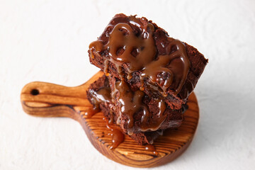 Wooden board with pieces of tasty chocolate brownie on white background