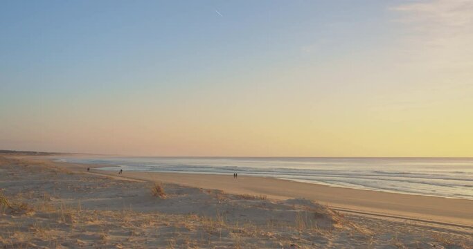 Peaceful Sandy Beach At Sunset With Tiny Images Of People Walking In The Background. - Wide Shot
