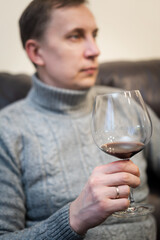 Relaxed serene rich lonely middle aged single man drinking red wine relaxing on sofa at home, enjoying resting sitting on couch holding glass tasting and reflecting.