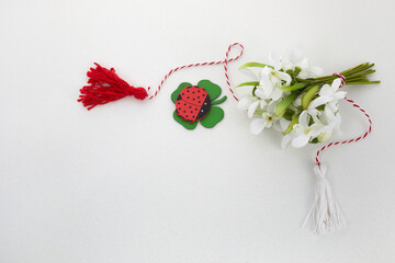 Bouquet of snowdrops on white background with red and white rope and lalybug. First of march celebration Martisor.