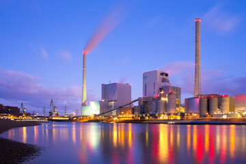 Large illuminated coal power plant with reflected lights in the water of a river