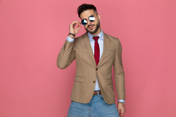 sexy businessman gently adjusting his sunglasses and posing