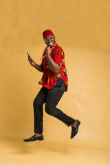 Igbo Traditionally Dressed Business Man in Mid Air with Phone in Hand Side View