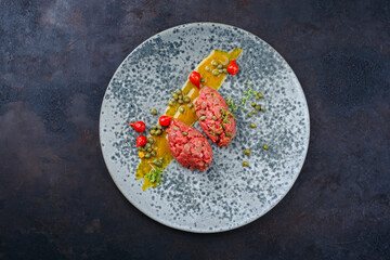 Modern Style rohes Gourmet Tartar vom Rinderfilet mit Biquiho Chili und Kapern serviert als Draufsicht auf einem Nordic Design Teller mit Textfreiraum