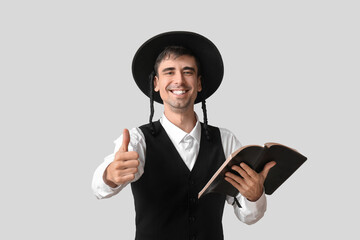Hasidic Jewish man with Torah showing thumb-up on light background