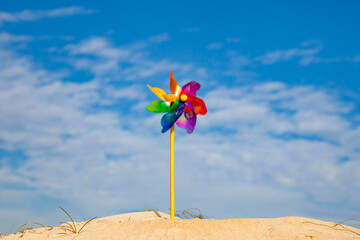children's toy wind propeller in the sand as a symbol of renewable wind energy