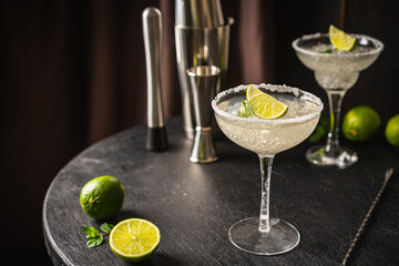Margarita cocktail with lime and ice on dark wooden table with copy space. Classic Margarita and Daiquiri Cocktail.
