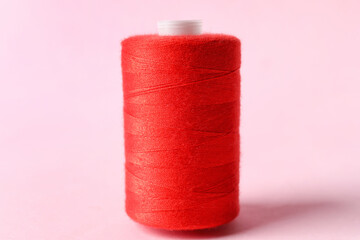 Red sewing thread spool on color background
