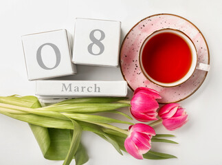Calendar, cup of tea and flowers for International Women's Day celebration on white background