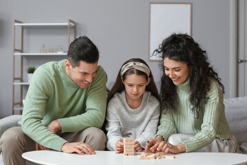 Happy family in warm sweaters playing jenga game at home