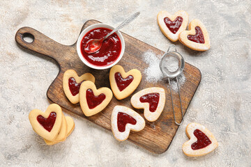 Board with tasty cookies and jam for Valentine's Day celebration on light background