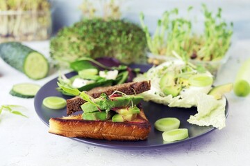 Sandwiches with avocado, boiled eggs, leek and arugula, sprinkled with fresh micro green sprouts, on a wooden board, natural ingredients, healthy food