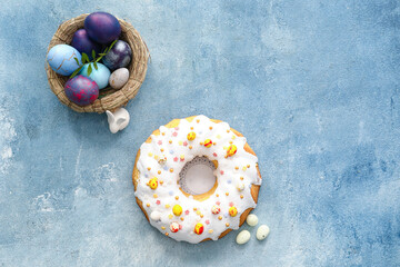 Tasty Easter cake and basket with eggs on blue background