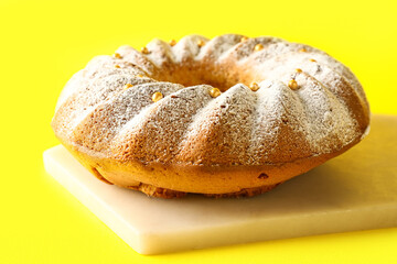 Board with tasty Easter cake on yellow background