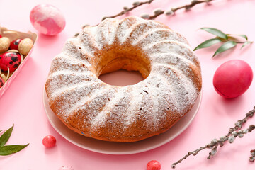 Plate with tasty Easter cake and eggs on pink background