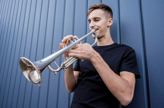 Young Street Musician Playing The Trumpet Near The Big Blue Wall