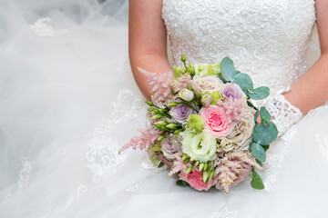 Beautiful bride in a wedding dress holding a bouquet of pink roses. White background. Text space.
