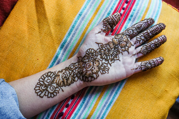 woman's hand freshly decorated with flower motifs in henna paste