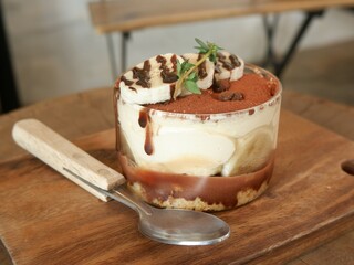 A cup of Banoffee with mini spoon on a wood dish