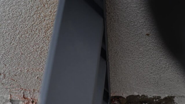 Close up shot on hands of man using rivet plier to join metal profiles to the fence rails. Handyman attaching metal parts of blinds fence with tool