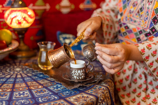 Pouring turkish coffee from cezve into cup