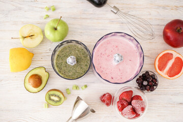 Plastic electrical hand blender and accessories with fruit on wooden background. Flat lay.