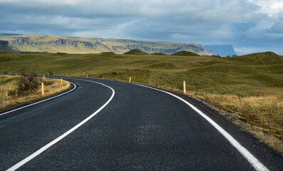 Highway road and mountain view during auto trip in Iceland. Spectacular Icelandic landscape with  scenic nature: fjords, fields, clouds, glaciers, waterfalls.