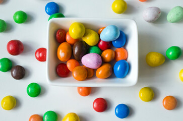 Close up of colorful chocolate buttons on a white background.