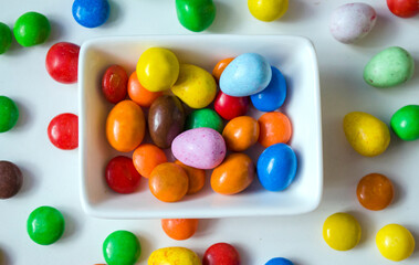 Close up of colorful chocolate buttons on a white background.