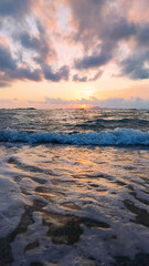 Beautiful sunset over sea. Colorful sky with clouds and waves from the beach.