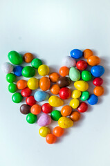 small multi-colored sweets in the form of a heart on a white background