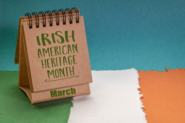 March Irish American Heritage Month - handwriting in a desktop calendar against  paper abstract in colors of national flag of Ireland (green, white and orange), reminder of cultural event
