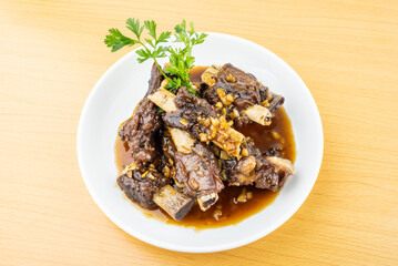 A plate of braised beef ribs on a wooden table