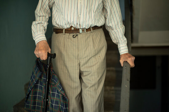 Pensioner goes down stairs. Grandpa walks down steps. Old man in Russia. - Powered by Adobe