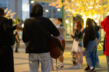 Street musician with guitar. Performance in square. Singer performs song.