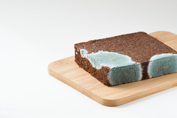 Pumpernickel bread with mold placed on wooden cutting board. Isolated.