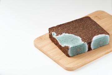 Pumpernickel bread with mold placed on wooden cutting board. Isolated.