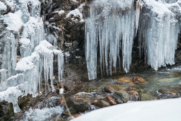 frozen waterfall in the alps hanging from the rocks ata cold winter day