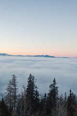 Amazing inversion over the valley with big snowy mountains on backround. Foggy and misty sunrise on hills.