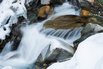 arctic landscape of frozen water from a mountain creek in long exposure photography at a cold winter day