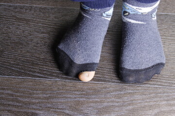 Fototapeta na wymiar Worn out socks with a hole and toes sticking out of them on wooden floor.