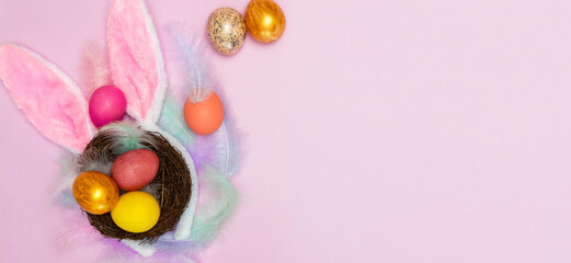happy Easter. Flatley. Banner. Colorful eggs in a nest on a pink background with hare ears. Horizontally. From above.