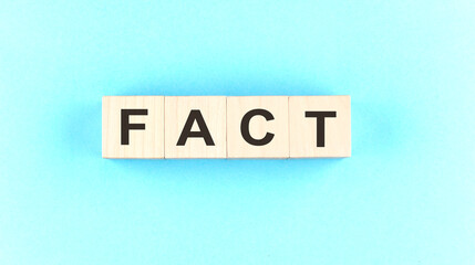 Wooden cube block with text FACT on the blue background