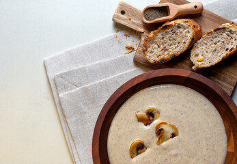 Creamy Mushroom Soup on wooden bowl on napkin, wooden background
