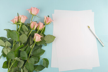 Pink roses and paper for text on the blue background, copy space